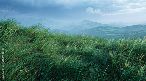 A scenic meadow with grass swaying in the wind and mountains in the distance under cloudy sky