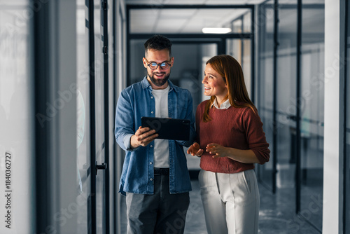 Two Professionals Discuss Work on a Tablet in a Modern Office