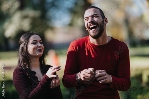 Fényképezés Two friends laugh together in a sunny park, enjoying a light, candid moment outdoors