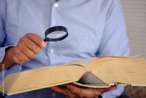 Foto Searching for specific information or words in a book with a magnifying glass