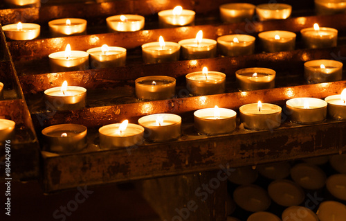 Rows of glowing candles inside a Catholic church, lit for prayer, remembrance, and commemoration of loved ones. The warm candlelight creates an atmosphere of peace, spirituality, and hope.