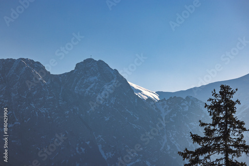 Fototapeta Naklejka Na Ścianę i Meble -  Giewont peak in Tatra Mountains above Zakopane town in Poland, Europe. A majestic mountain peak crowned with snow, piercing the clear blue sky, captured in a scenic mountain landscape.
