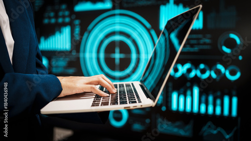 Professional working on laptop in front of futuristic digital dashboards, highlighting data analytics, cybersecurity insights, real-time visual information that reflect modern technology.