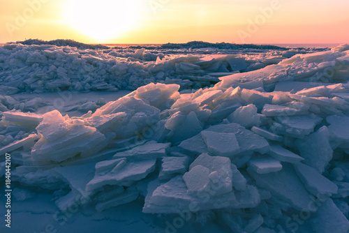 A dramatic winter scene shows broken ice chunks piled along a frozen sea