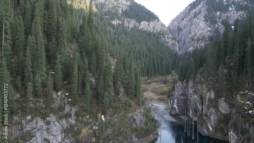 Scenic view of a river winding through dense evergreen forests and rocky cliffs, showcasing the natural beauty of the landscape as the camera pans right, revealing more of the serene environment
