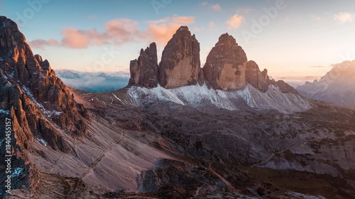 Alpine landscape of sunset over Tre Cime mountain peak and mountain hut during autumn in Dolomites, Italy