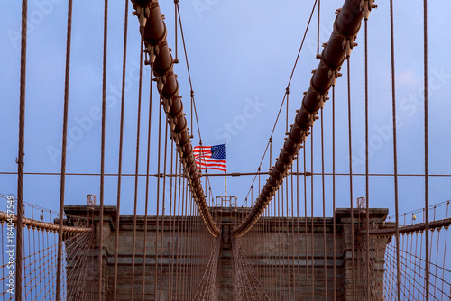 Brooklyn Bridge with American flag on American city during an evening walk across bridge