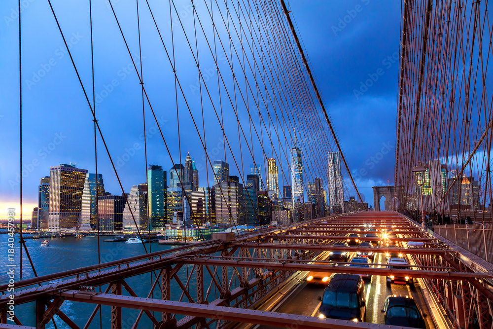 Obraz premium Brooklyn Bridge connects Manhattan Brooklyn with NY city lights traffic at dusk