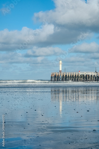 Nieuwpoort, West-Vlaanderen, Belgium, Ocotber 25th, 2025, seaside beacon scene, coastal image for branding, reflected clouds and gentle surf on pier