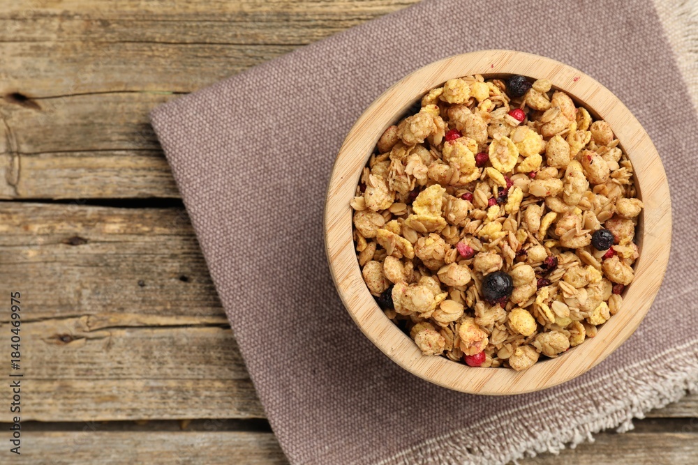 Fototapeta premium Tasty granola with dried fruits in bowl on wooden table, top view. Space for text
