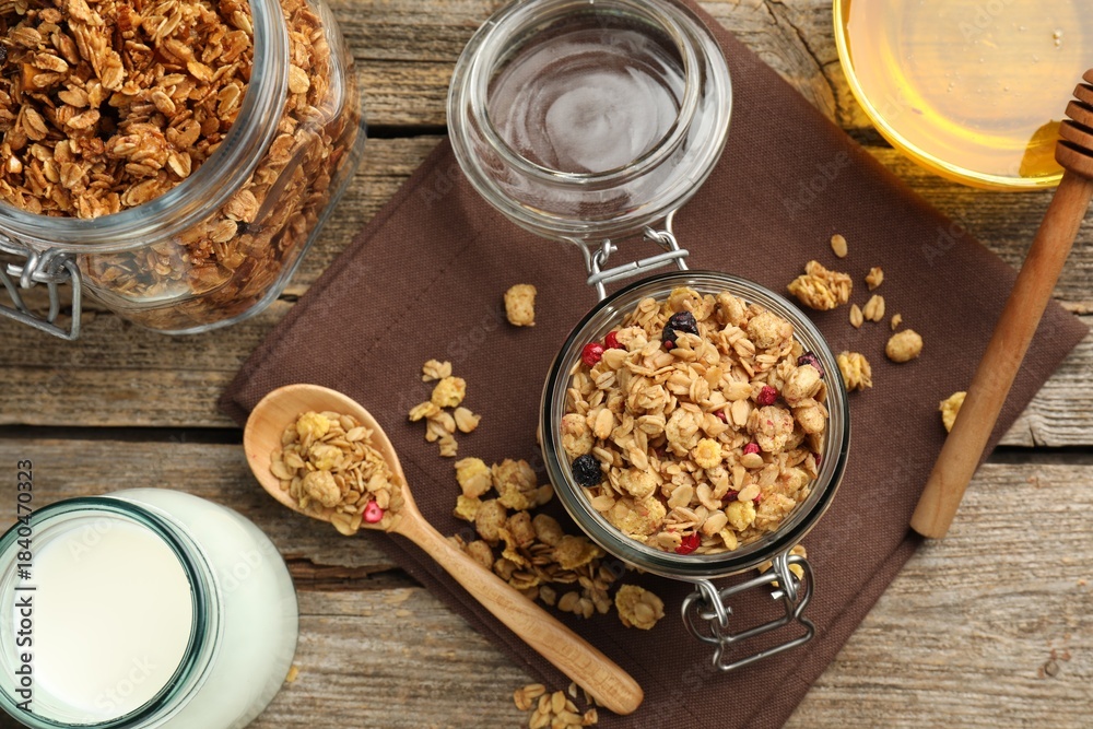 Fototapeta premium Tasty granola with dried fruits, milk and honey on wooden table, flat lay