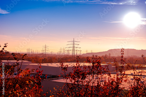 Der Himmel brennt in einem spektakulären Übergang von tiefem Blau zu hellem, sanftem Orange, während die Sonne selbst wie ein gleißendes Versprechen am Horizont steht. Vor dieser epischen Kulisse erhe