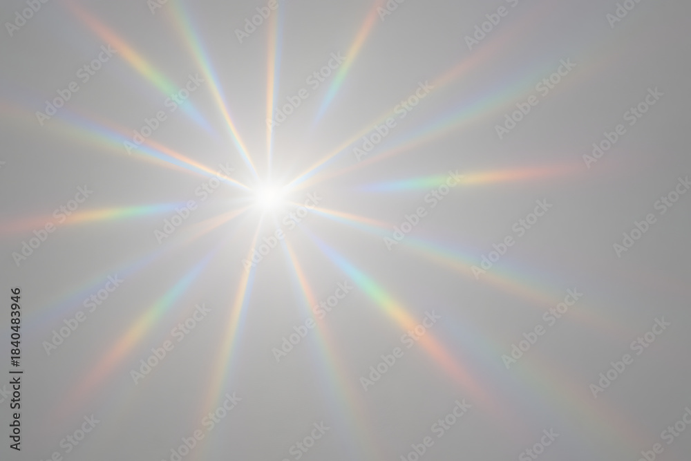 Fototapeta premium Sunlight Dispersion: The bright sun radiating out beams of rainbow light across the light-grey background, this image captures the beauty of light and the spectacle it creates.