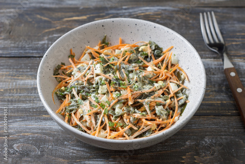 Seaweed and carrot salad mixed with diced egg and creamy dressing in rustic ceramic bowl 