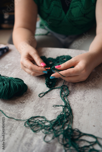 unrecognizable woman crocheting new item from green yard