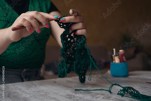 unrecognizable woman crocheting new item from green yard