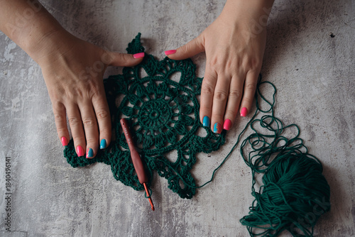 hands of woman crocheting square shape napkin from green yard