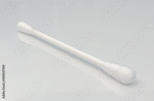 close-up view of single cotton swab on light colored reflective background