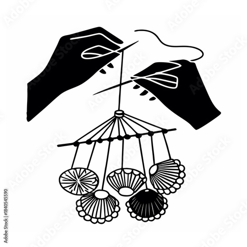 Hands create a mobile with shells in a workshop setting during the daytime