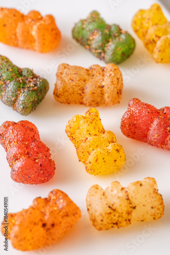 Colorful gummy bears with chili lime seasoning displayed on clean white plate
