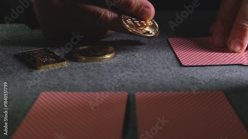 Male hands dealing playing cards and gambling with physical bitcoin coins on a grey felt table