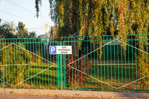 Εκτύπωση καμβά Green metal fence section features a parking sign for churchgoers framed by lush