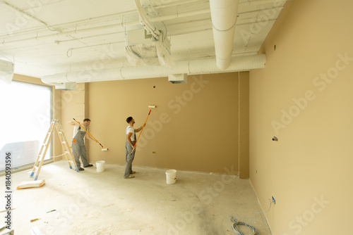 Workers painting a beige wa...