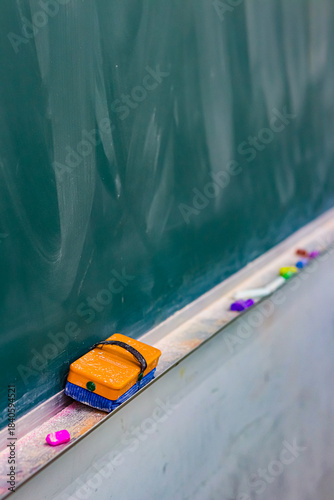 黒板に並ぶ黒板消しとチョークの学校教室の静かな一場面／Eraser and chalk on classroom blackboard in quiet school scene