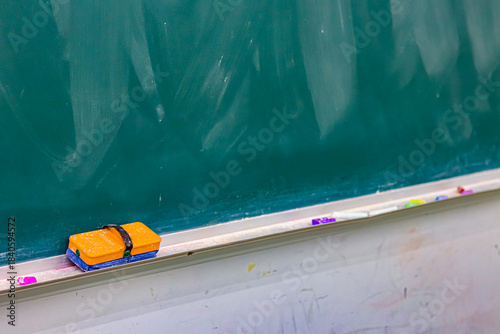 黒板に並ぶ黒板消しとチョークの学校教室の静かな一場面／Eraser and chalk on classroom blackboard in quiet school scene
