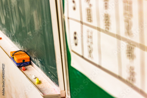 黒板に並ぶ黒板消しとチョークの学校教室の静かな一場面／Eraser and chalk on classroom blackboard in quiet school scene
