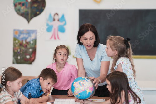 Quadro em tela Female teacher with kids in geography class looking at globe