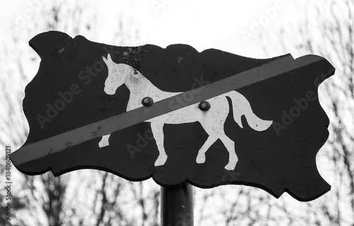 Path restricted for horse riding. No horse riding sign against blurry forest trees background . Vincennes forest, Paris, France. Black white historic photo.