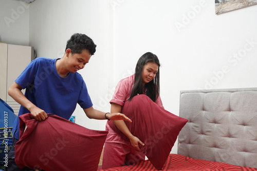 Couple Making Bed Together Indoors