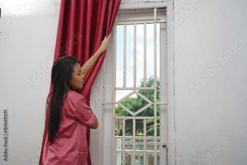 Woman Opening Red Curtains by Window