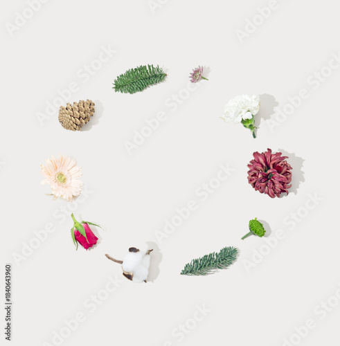 Festive holiday background created with natural pine branches, pine cones and seasonal flowers. Minimal, organic Christmas flat lay with space for text. Ideal for winter promotions, greeting cards....