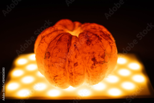 Vibrant orange pumpkin illuminated from below, showcasing its textured surface and unique shape, creating a warm and inviting atmosphere for autumn celebrations
