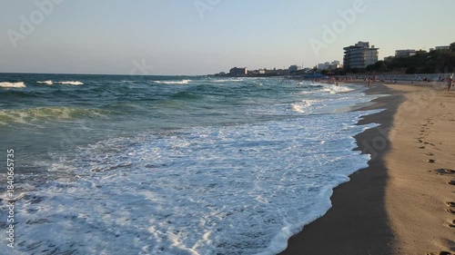 Calm waves touch the warm beach under clear skies.