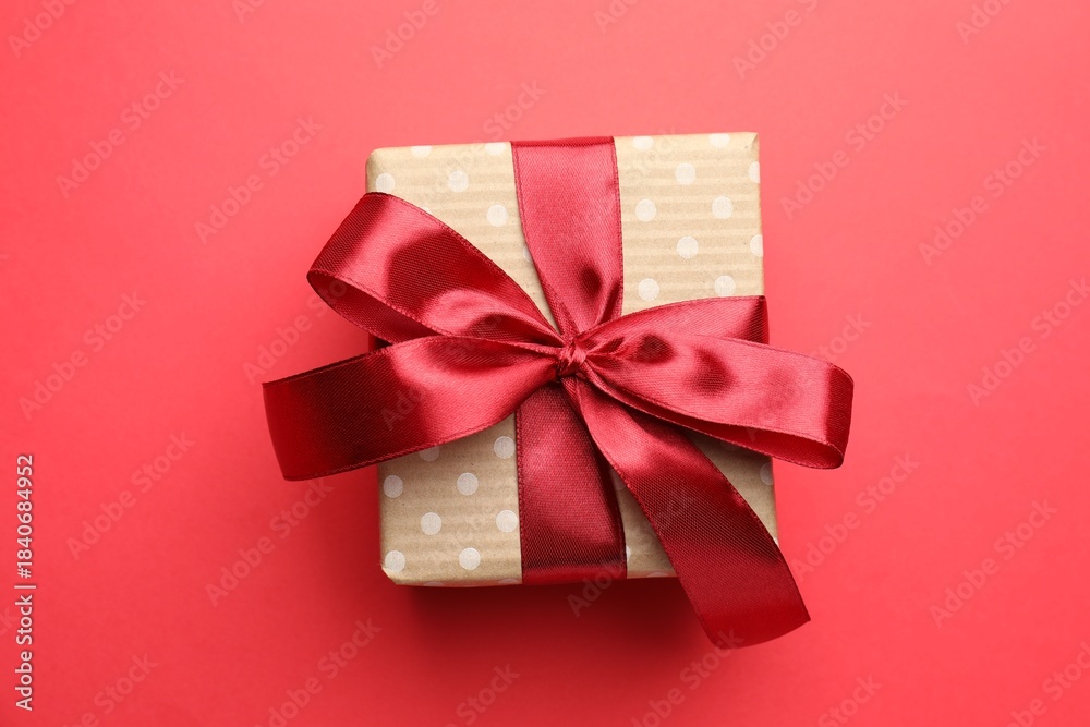 Fototapeta premium Beautiful gift with bow on red background, top view