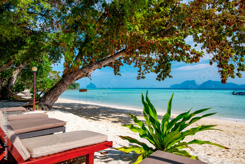 Sun loungers inviting travelers to relax on a white sand beach, featuring clear turquoise water, a shaded swing, and distant islands, creating a peaceful scene in Koh Kradan, Trang, Thailand