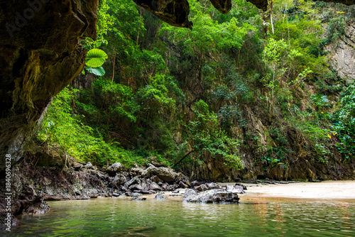 Emerald Cave's hidden beach and verdant limestone cliffs frame the sparkling green water, offering a serene escape within a rich tropical ecosystem, a natural wonder in Kantang, Trang