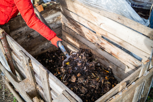 Turning Compost with a Garden Fork in a Wooden Compost Bin