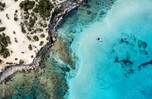 Drone aerial view of boats in turquoise ocean water by coastline. Blue lagoon
