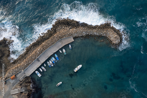 Drone aerial scenery of fishing boats moored at the harbor at the breakwater. Stormy waves at sea Peyia, Cyprus