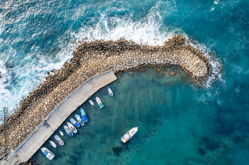 Drone aerial scenery of fishing boats moored at the harbor at the breakwater. Stormy waves at sea Peyia, Cyprus