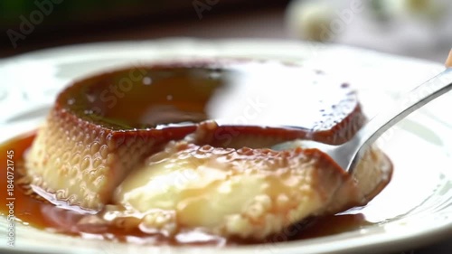 Spoon taking a bite of flan dessert on a plate