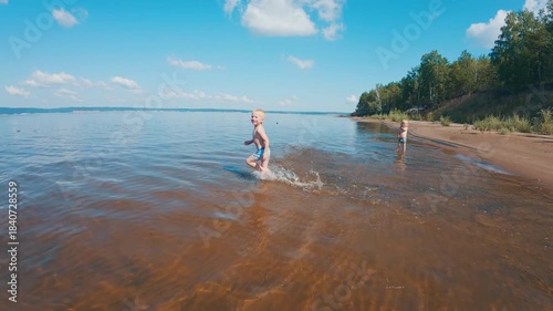 Summer family fun. Kids run around on the summer beach and in the river