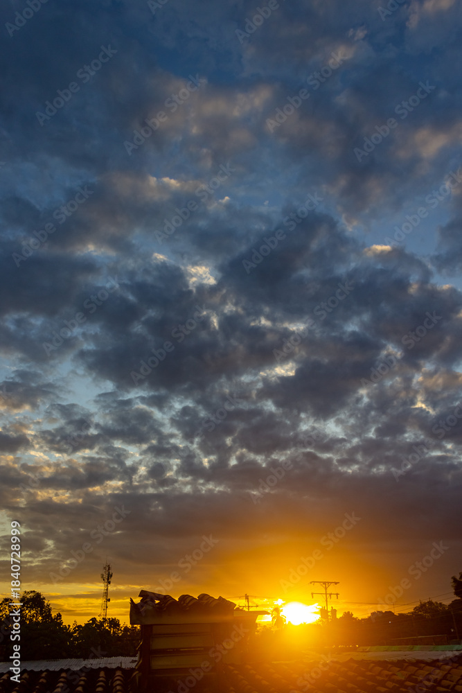 Fototapeta premium Sunset over the city with dramatic clouds and sunbeams.