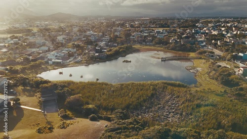 Aerial view of the lake in the middle of a neighborhood. Lake surrounded by living buildings during sunset. Lagoa Chica in the town of Campeche, near the city of Florianopolis, Brazil