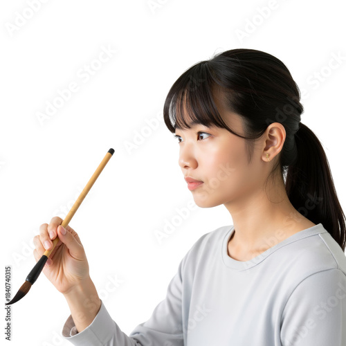 Focused asian woman holding calligraphy brush in creative moment concept