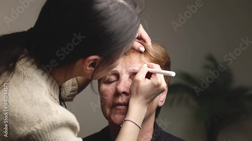One young cosmetologist colors the eyebrows of an older woman.